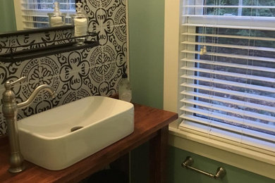 Example of a small country black and white tile and porcelain tile porcelain tile bathroom design in Bridgeport with open cabinets, brown cabinets, a two-piece toilet, green walls, a vessel sink, wood countertops and brown countertops
