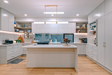 Design ideas for a large traditional l-shaped open plan kitchen in Melbourne with a single-bowl sink, recessed-panel cabinets, quartz benchtops, grey splashback, engineered quartz splashback, black appliances, with island and grey benchtop.