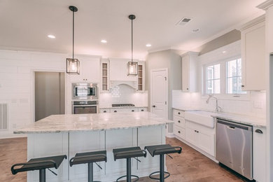 Country medium tone wood floor kitchen photo in Nashville with a farmhouse sink, recessed-panel cabinets, white cabinets, granite countertops, white backsplash, subway tile backsplash, stainless steel appliances and an island