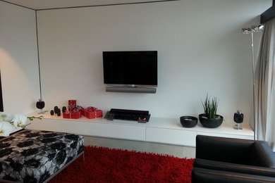 This is an example of a mid-sized contemporary open concept family room in Bonn with white walls and a wall-mounted tv.