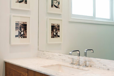 Example of a mid-sized trendy 3/4 gray tile and marble tile porcelain tile and gray floor corner shower design in Other with flat-panel cabinets, dark wood cabinets, a one-piece toilet, white walls, an undermount sink, marble countertops, a hinged shower door and white countertops