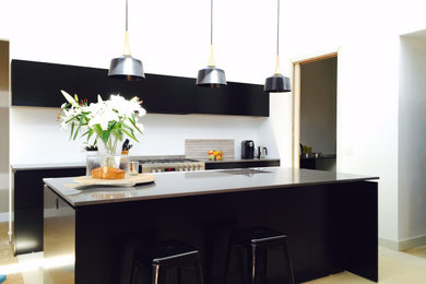 Photo of a mid-sized contemporary galley open plan kitchen in Melbourne with an undermount sink, flat-panel cabinets, black cabinets, quartz benchtops, white splashback, stainless steel appliances, ceramic floors, with island and black benchtop.