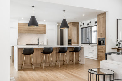 Inspiration for a huge contemporary medium tone wood floor kitchen remodel in Toronto with a double-bowl sink, shaker cabinets, quartz countertops, white backsplash, quartz backsplash, paneled appliances, two islands and white countertops