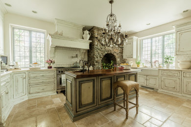 This is an example of a traditional u-shaped kitchen in New York with raised-panel cabinets, white splashback, stainless steel appliances, with island, beige floor, beige benchtop and distressed cabinets.