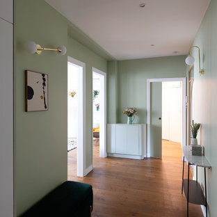 パリの大きい両開きドアコンテンポラリースタイルのおしゃれな玄関ロビー (緑の壁、濃色無垢フローリング、金属製ドア、茶色い床) の写真