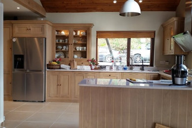 Photo of a medium sized farmhouse u-shaped kitchen/diner in Other with a submerged sink, recessed-panel cabinets, light wood cabinets, quartz worktops, stainless steel appliances and a breakfast bar.