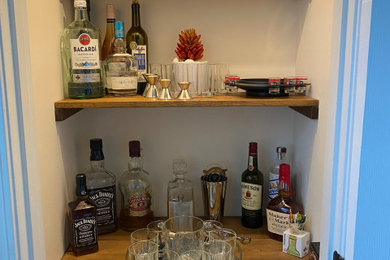 Small elegant home bar photo in Atlanta with floating shelves, brown cabinets, wood countertops and brown countertops