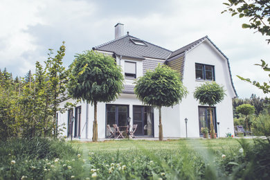 Großes, Zweistöckiges Country Einfamilienhaus mit Putzfassade, weißer Fassadenfarbe, Mansardendach, Ziegeldach und grauem Dach in Stuttgart
