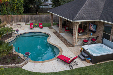 Inspiration for a mid-sized tropical backyard stamped concrete and kidney-shaped hot tub remodel in Houston