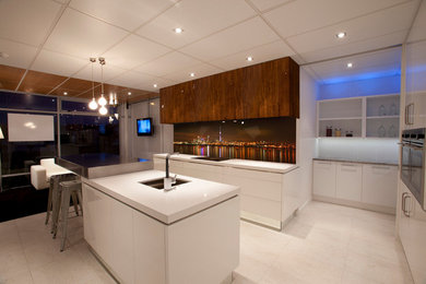 Large contemporary eat-in kitchen in Auckland with a double-bowl sink, white cabinets, solid surface benchtops, glass sheet splashback, stainless steel appliances, porcelain floors, with island and white floor.