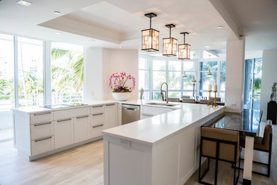 Inspiration for a mid-sized contemporary u-shaped open plan kitchen in Miami with recessed-panel cabinets, white cabinets, quartz benchtops, a peninsula, a double-bowl sink, white splashback, stone slab splashback, stainless steel appliances, light hardwood floors and beige floor.