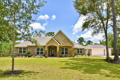 Large traditional beige one-story stone exterior home idea in Houston with a clipped gable roof