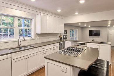 Large trendy u-shaped medium tone wood floor and brown floor open concept kitchen photo in Other with an undermount sink, white cabinets, quartz countertops, subway tile backsplash, stainless steel appliances, an island, shaker cabinets and white backsplash