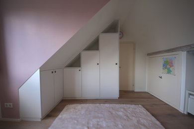 Kleines Modernes Kinderzimmer mit Spielecke, rosa Wandfarbe, hellem Holzboden und braunem Boden in Düsseldorf