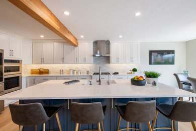 Example of a mid-sized minimalist galley light wood floor and exposed beam eat-in kitchen design in Other with a double-bowl sink, shaker cabinets, white cabinets, quartzite countertops, gray backsplash, stone tile backsplash, stainless steel appliances, an island and white countertops