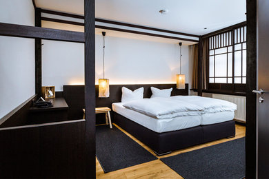 Mittelgroßes Asiatisches Gästezimmer mit weißer Wandfarbe und hellem Holzboden in München