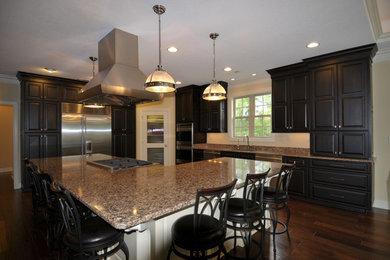Inspiration for a large transitional l-shaped medium tone wood floor eat-in kitchen remodel in New York with an undermount sink, raised-panel cabinets, dark wood cabinets, quartz countertops, stainless steel appliances and an island