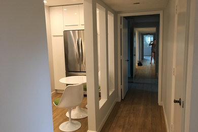 Mid-sized minimalist u-shaped light wood floor enclosed kitchen photo in Orange County with an undermount sink, flat-panel cabinets, white cabinets, quartz countertops, white backsplash, stone slab backsplash and stainless steel appliances