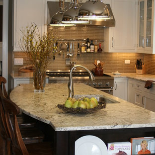 Idées déco pour une arrière-cuisine classique en U de taille moyenne avec un électroménager en acier inoxydable, un plan de travail en granite, un évier encastré, un placard avec porte à panneau encastré, des portes de placard blanches, une crédence marron, une crédence en carreau briquette, un sol en bois brun et un îlot central.