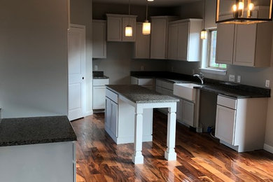 Inspiration for a timeless eat-in kitchen remodel in Detroit with a farmhouse sink, shaker cabinets, gray cabinets, granite countertops and an island