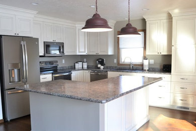 Inspiration for a mid-sized transitional l-shaped dark wood floor and brown floor eat-in kitchen remodel in Other with a drop-in sink, raised-panel cabinets, white cabinets, laminate countertops, stainless steel appliances and an island