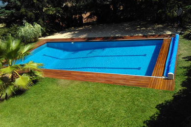 Large contemporary rectangular lap pool in Other with a pool house and decking.