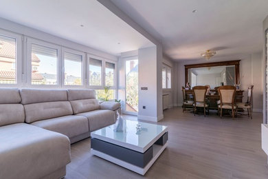 Modelo de comedor contemporáneo grande abierto sin chimenea con paredes grises, suelo laminado y suelo gris