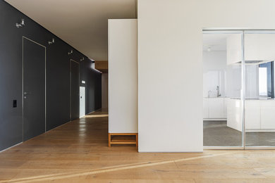На фото: большая открытая гостиная комната в стиле модернизм с белыми стенами и светлым паркетным полом без камина