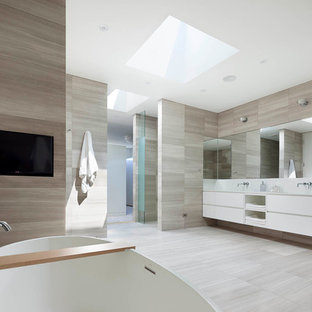 Ispirazione per una grande stanza da bagno padronale minimalista con ante lisce, ante bianche, vasca freestanding, doccia a filo pavimento, WC monopezzo, piastrelle grigie, piastrelle in pietra, pareti grigie, pavimento in pietra calcarea, lavabo rettangolare e top in superficie solida