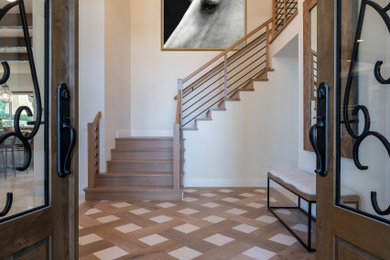 Example of a large mountain style limestone floor and beige floor entryway design in Orange County with white walls and a brown front door