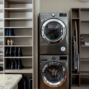 Ejemplo de lavadero multiusos, de estilo de casa de campo, grande, con armarios abiertos, puertas de armario de madera clara, encimera de mármol, suelo de madera en tonos medios, lavadora y secadora apiladas, suelo marrón y encimeras multicolor