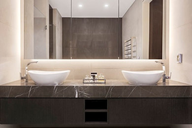 Inspiration for a large contemporary master wet room bathroom in Sydney with flat-panel cabinets, dark wood cabinets, a freestanding tub, a wall-mount toilet, beige tile, ceramic tile, beige walls, a pedestal sink, marble benchtops, a hinged shower door and grey benchtops.