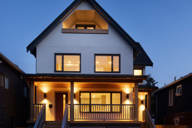 Large trendy white four-story stucco exterior home photo in Vancouver with a shingle roof and a black roof