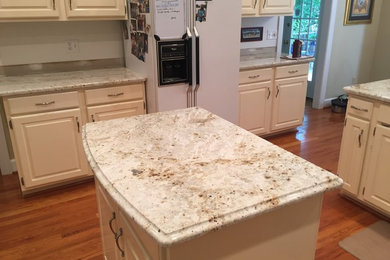 Mid-sized elegant u-shaped medium tone wood floor eat-in kitchen photo in Other with raised-panel cabinets, beige cabinets, granite countertops, white appliances, an island, white backsplash, ceramic backsplash and a double-bowl sink
