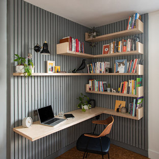 Foto på ett mellanstort funkis hemmabibliotek, med grå väggar, korkgolv, ett inbyggt skrivbord och brunt golv