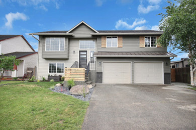 Example of a large country gray split-level wood house exterior design in Seattle with a mixed material roof