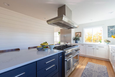 Mittelgroße Skandinavische Küche in L-Form mit Schrankfronten im Shaker-Stil, blauen Schränken, Quarzwerkstein-Arbeitsplatte, Küchenrückwand in Weiß, braunem Holzboden, Kücheninsel, braunem Boden und weißer Arbeitsplatte in Minneapolis