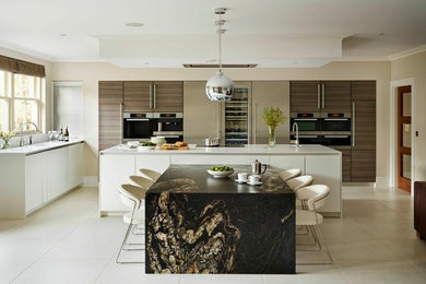 This is an example of a large contemporary kitchen/diner in Essex with flat-panel cabinets, white cabinets, an island and integrated appliances.