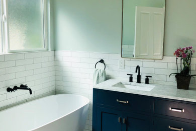Freestanding bathtub - coastal white tile marble floor freestanding bathtub idea in Los Angeles with blue cabinets and marble countertops