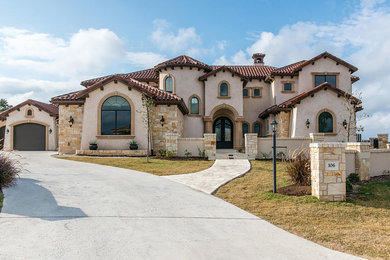 This is an example of a mediterranean two-storey stucco exterior in Austin with a gable roof.