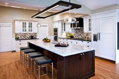 Mid-sized elegant l-shaped medium tone wood floor and brown floor open concept kitchen photo in Toronto with a double-bowl sink, shaker cabinets, white cabinets, granite countertops, brown backsplash, stone tile backsplash, paneled appliances, an island and gray countertops