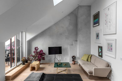 Nordisches Wohnzimmer ohne Kamin mit grauer Wandfarbe, hellem Holzboden und freistehendem TV in Stockholm