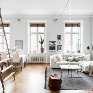 Immagine di un soggiorno scandinavo aperto e di medie dimensioni con pareti grigie, pavimento in legno massello medio e nessuna TV
