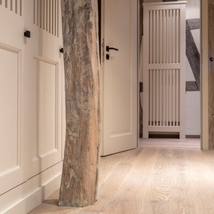Diseño de armario y vestidor campestre, grande, con armarios con rebordes decorativos, puertas de armario grises, suelo de madera pintada y suelo gris