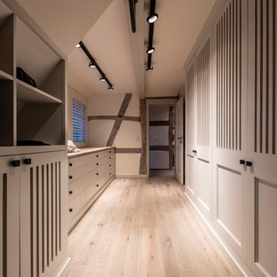 Foto di una grande cabina armadio per donna country con ante grigie, pavimento in legno verniciato, pavimento grigio e ante a filo