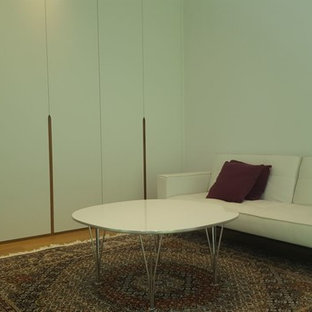 Ejemplo de vestidor unisex, actual, de tamaño medio, con armarios con paneles lisos, puertas de armario blancas, suelo laminado y suelo marrón