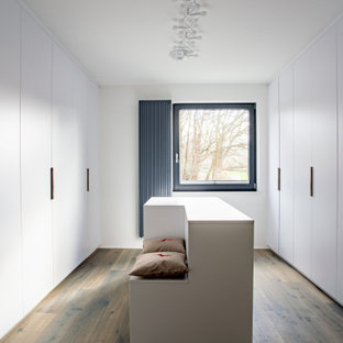 Neutrales, Großes Modernes Ankleidezimmer mit Ankleidebereich, flächenbündigen Schrankfronten, weißen Schränken, dunklem Holzboden und braunem Boden in Dortmund