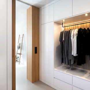 Imagen de armario vestidor unisex, escandinavo, con armarios con paneles lisos, puertas de armario blancas, suelo de cemento y suelo gris