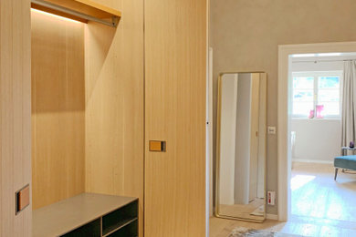 Diseño de armario unisex actual de tamaño medio con armarios con paneles con relieve, puertas de armario de madera clara, suelo de madera clara y suelo beige