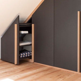 Idéer för ett mellanstort modernt walk-in-closet för könsneutrala, med släta luckor, svarta skåp, ljust trägolv och brunt golv